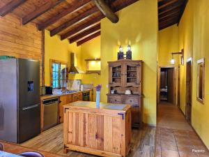 a large kitchen with yellow walls and a refrigerator at Casa das Devesas in Caldelas