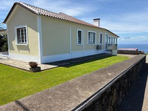 a small white house with the ocean in the background at Retiro da Ribeira in Angra do Heroísmo