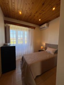 a bedroom with a large bed and a window at Retiro da Ribeira in Angra do Heroísmo