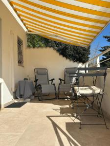 eine Terrasse mit Stühlen, einem Tisch und einem Sonnenschirm in der Unterkunft Elo'Nco in Caderousse