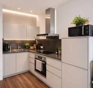 a kitchen with white cabinets and stainless steel appliances at Marienplatz Design Apartment - Historic Center in Munich