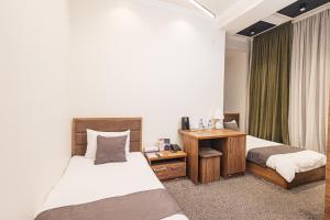 a hotel room with two beds and a desk at Merhaba Hotel, Fergana in Fergana