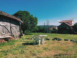 a table and chair in a field next to a barn at Casa Urgueira in Pendilhe