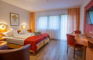 a hotel room with a bed and a desk at Hotel Die Kleine Blume in Erfweiler