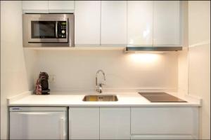 a white kitchen with a sink and a microwave at Sun Studio Valencia in Valencia