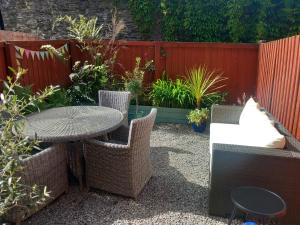 a patio with a table and chairs and a fence at Bossell Cottage Devon in Buckfastleigh