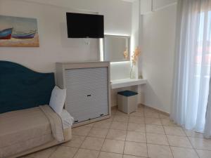 a bedroom with a bed and a tv on the wall at Filomeni Studios in Pefkochori