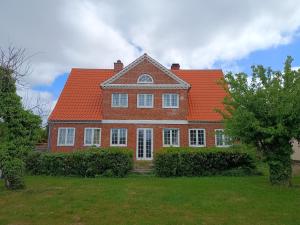 a large red brick house with an orange roof at Aakirkeby Bed and Breakfast in Åkirkeby