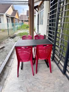 a black table and red chairs on a patio at MiD Guest House in Gambang