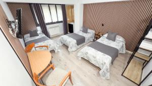 a room with three beds and a table and chairs at PENSIÓN PESQUERO in Burgos +32 photos