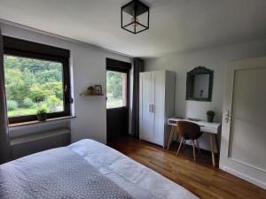 a bedroom with a bed and a desk and a window at Ferienwohnung Tutbach in Jünkerath