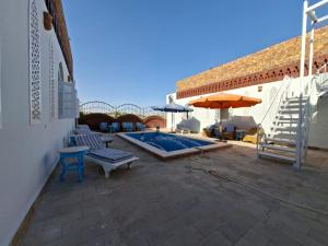 a patio with a pool and chairs and an umbrella at Nefertiti Guest House in ‘Ezbet Abu Ḥabashi