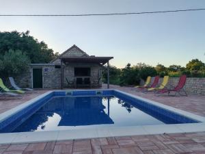 a swimming pool with chairs and a gazebo at Božini dvori in Drniš