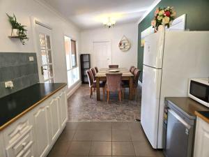 a kitchen with a table and a white refrigerator at Whispering Woods Pool Sauna in Maryborough