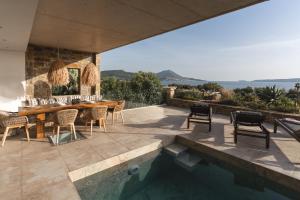 a patio with a table and chairs next to a swimming pool at Villa Ammos with Private Pool, Sauna & Seaview in Gialova