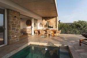 a patio with a table and chairs and a swimming pool at Villa Ammos with Private Pool, Sauna & Seaview in Gialova