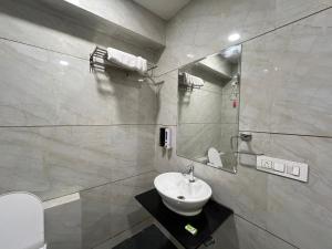 a bathroom with a sink and a toilet and a mirror at Hotel VAAYU Stay IGI Airport in New Delhi