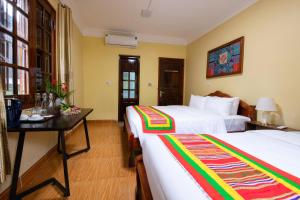 a hotel room with two beds and a table at Tada Moc Chau - Villa & Local Kitchen in Mộc Châu +89 photos