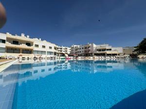 a large swimming pool with blue water in front of buildings at Dunas Sea and Sun Alvor in Alvor