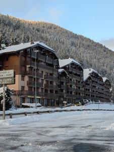 a large apartment building with a snow covered mountain at Les Portes du Soleil Studio in Le Biot