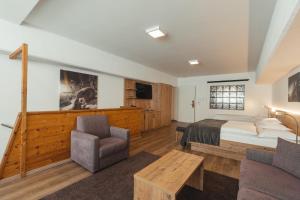 a bedroom with a bed and a couch and a chair at Zermatt Budget Rooms at Alpen Resort, Spa & Dining in Zermatt