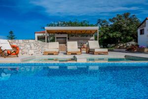 a swimming pool with chairs and a gazebo at Minos Villa in Arménoi