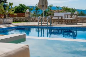 a swimming pool with a table and chairs and an umbrella at Minos Villa in Arménoi