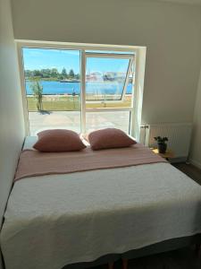 a bed with two pillows in front of a window at South Harbour Studios in Vordingborg