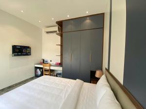 a bedroom with a large white bed and a desk at VMona Hotel in Thôn Kim Long (1)