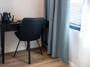a black desk with a chair next to a window at Ruustinna Hotelli & B&B Majoitus in Saarijärvi