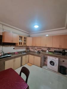 a kitchen with wooden cabinets and a table and a dishwasher at Appartement sselam fetouaki montagne view in Moulay Yacoub