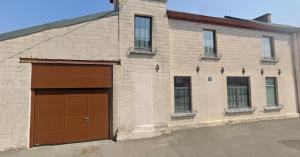 a brick building with a brown garage door at Large bright apartment in Lessines