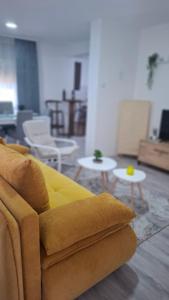 a yellow couch in a living room with tables at SAMI APARTMAN in Niš