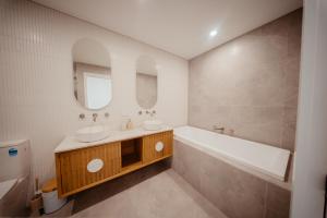 a bathroom with a tub and a sink and a bath tubermottermott at Coastal on Clarke in Portarlington +17 photos