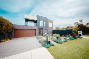 a brick house with a garden in front of it at Coastal on Clarke in Portarlington