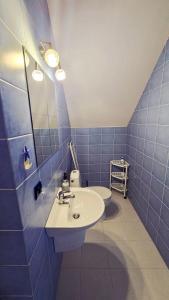 a blue tiled bathroom with a sink and a toilet at Villa Henry in Grzybowo