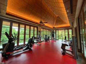a gym with treadmills and exercise equipment and windows at Baan Na Villa in Satuk