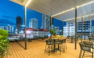 a balcony with tables and chairs and a city skyline at Intercity Hotel & Serviced Apartment Phnom Penh Downtown in Phnom Penh
