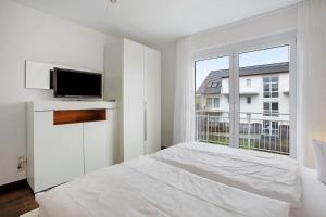 a white bedroom with a bed and a large window at Weinregion direkt vor der Tür erleben - Ferienwohnung Weinberg in Bad Bellingen