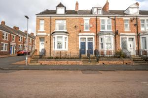a brick house with a blue door on a street at Sweet Home NE LTD in Gateshead