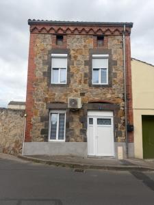 a brick building with two white doors on a street at Maison campagne proche A75 in Vergongheon