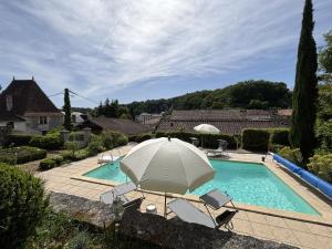 an umbrella and chairs next to a swimming pool at 9 Impasse Saint Martin in Brantôme