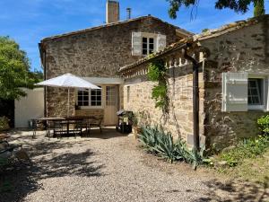 a stone house with a table and an umbrella at Domaine de Villedese in Montlaur