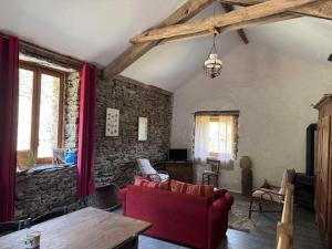 a living room with red furniture and a stone wall at La grange de Jean et Claude in Barre-des-Cévennes +14 photos
