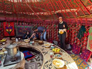 a group of people standing around a table in a tent at Jusup Guest House, Hostel horse riding tours to Son Kol and Karakol in Dzhangyaryk