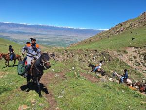 a group of people riding horses on a hill at Jusup Guest House, Hostel horse riding tours to Son Kol and Karakol in Dzhangyaryk