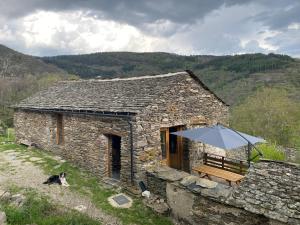 a stone building with a bench and an umbrella at La grange de Jean et Claude in Barre-des-Cévennes