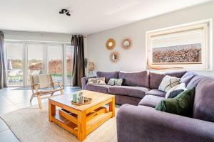 a living room with a purple couch and a table at Strandvilla met sauna in Westerhaar-Vriezenveensewijk