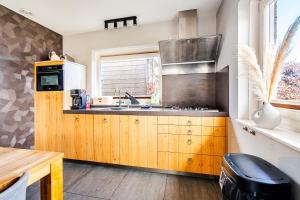 a kitchen with wooden cabinets and a sink at Strandvilla met sauna in Westerhaar-Vriezenveensewijk