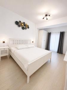 a white bedroom with a large white bed in a room at Eqinox apartments in Mamaia Sat/Năvodari